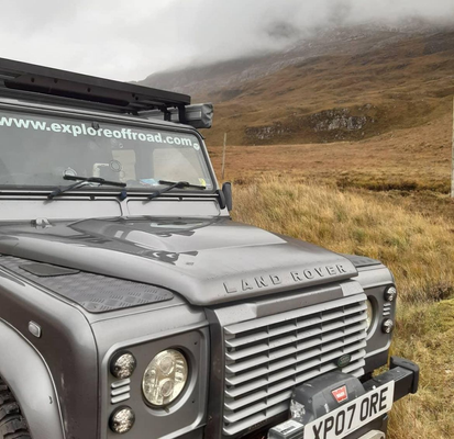 Close view of a grey Land Rover Defender with an expedition roof rack on an upland track.